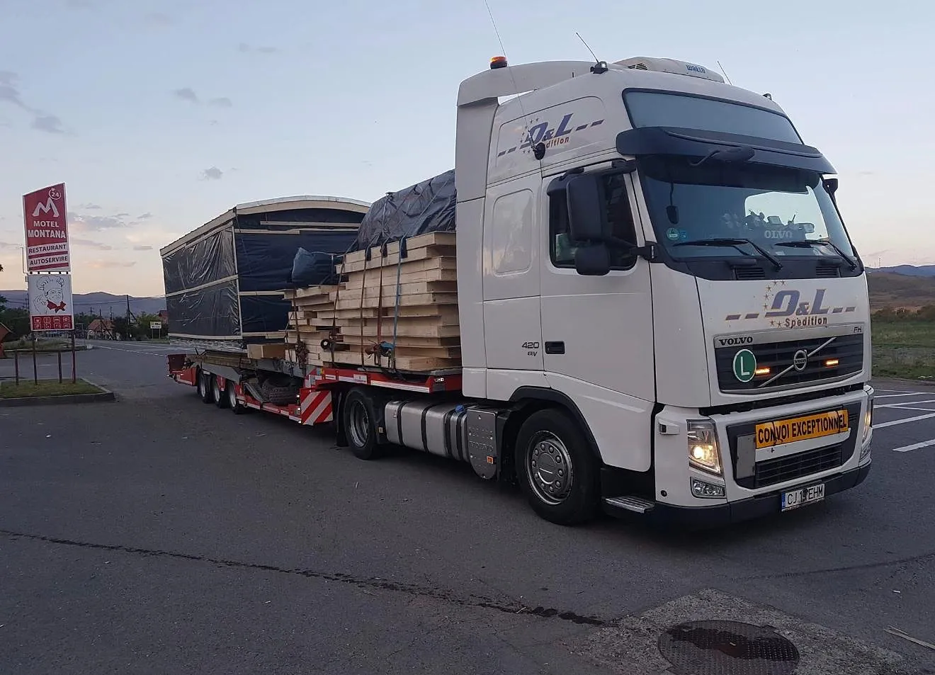 Casă modulară din lemn transportată pe platformă joasă, cu materialul de montaj, - OL Speditionwagon
