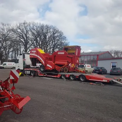 Combină de recoltat cartofi Grimme, încărcată pe platformă joasă. Utilajele de recoltat au gabarit mare și centru de greutate ridicat. - OL Speditionwagon