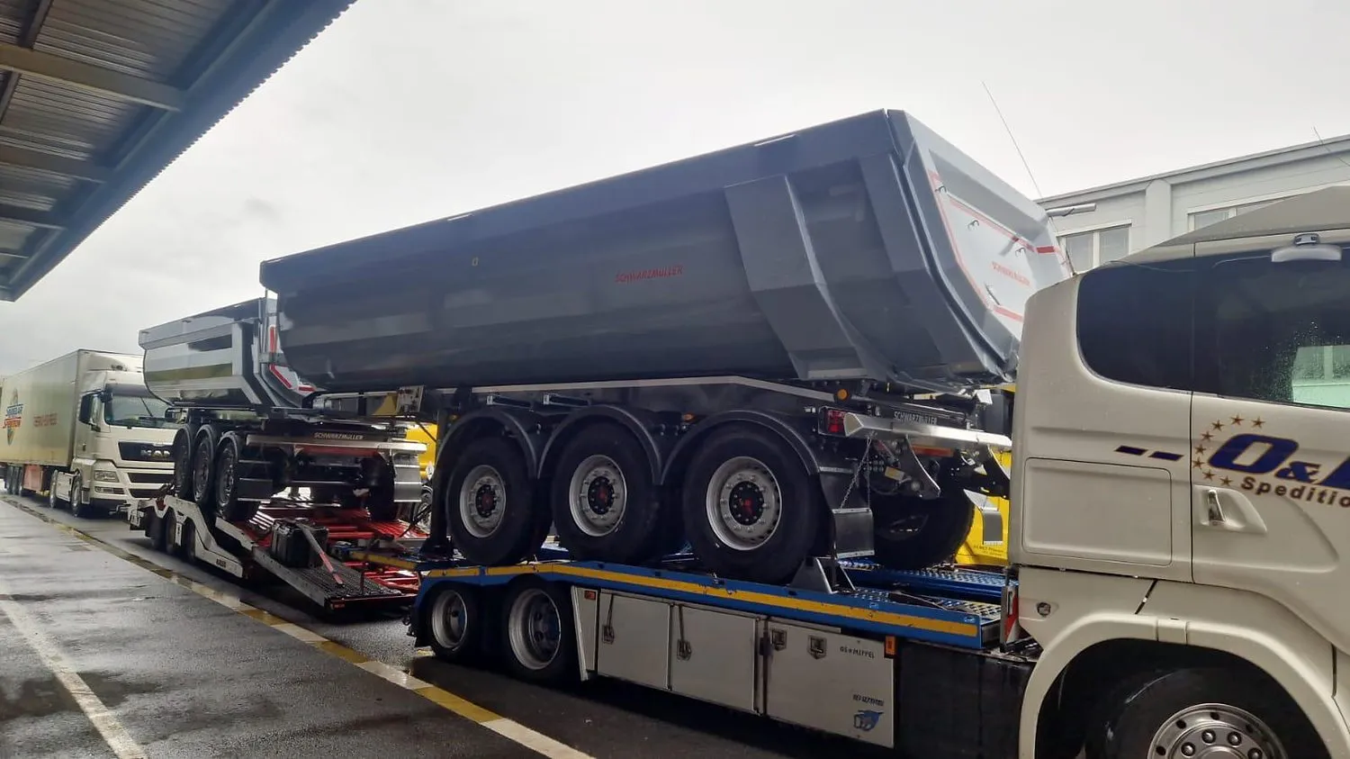 Două semiremorci basculante Schwarzmüller noi transportate pe aceeași platformă de OL Speditionwagon